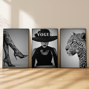 Könnte beinhalten: Set aus drei schwarz-weiß gerahmten Kunstdrucken. Einer zeigt eine Frau mit Hut mit dem Wort "VOGUE". Ein weiterer zeigt das Gesicht eines Leoparden, und der dritte Beine in Spitzenstrümpfen und High Heels.