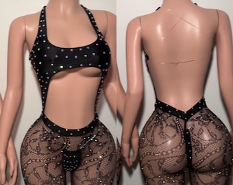 Könnte beinhalten: Schwarzer Body mit Neckholder und Cut-Out-Design, verziert mit schillernden Strasssteinen. Der untere Teil hat schwarze Spitzenleggings mit Strassakzenten. Der Rücken des Bodysuits ist tief ausgeschnitten.