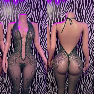 May include: A dark green, sleeveless, full-body fishnet bodysuit featuring a deep V-neckline with lace-up detailing, intricate floral-inspired patterns, and small embedded rhinestones. The garment has an open back design with a halter tie.