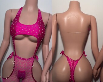 May include: A vibrant pink bodysuit adorned with rhinestones. The halterneck top has a keyhole detail, and the bottoms feature a garter design with matching rhinestones. The outfit is displayed on a mannequin.