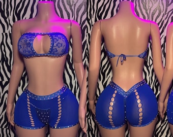 May include: A two-piece set consisting of a royal blue strapless lace bandeau top with a center cutout and matching royal blue shorts featuring side cutouts, vertical rows of circular openings, and silver stud embellishments along the trim.