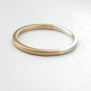 May include: A simple, thin gold and silver band ring. The ring is half gold and half silver.