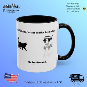 May include: White ceramic mug with a black interior and handle. The mug features the text "Schrödinger's cat walks into a bar" and "Or he doesn't..." along with a silhouette of a cat and bar patrons. The mug is designed and printed in the USA.