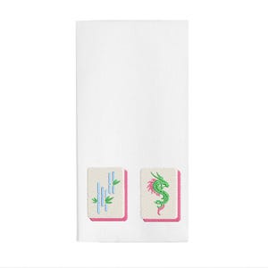 May include: White rectangular towel featuring embroidered Mahjong tiles. One tile shows bamboo stalks in blue and green, the other a green dragon with pink accents. Both tiles have a pink border.