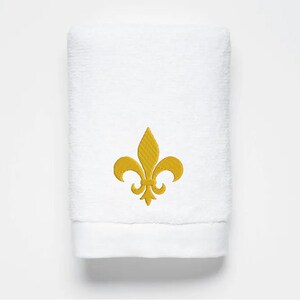 May include: White bath towel with a gold embroidered fleur-de-lis design.