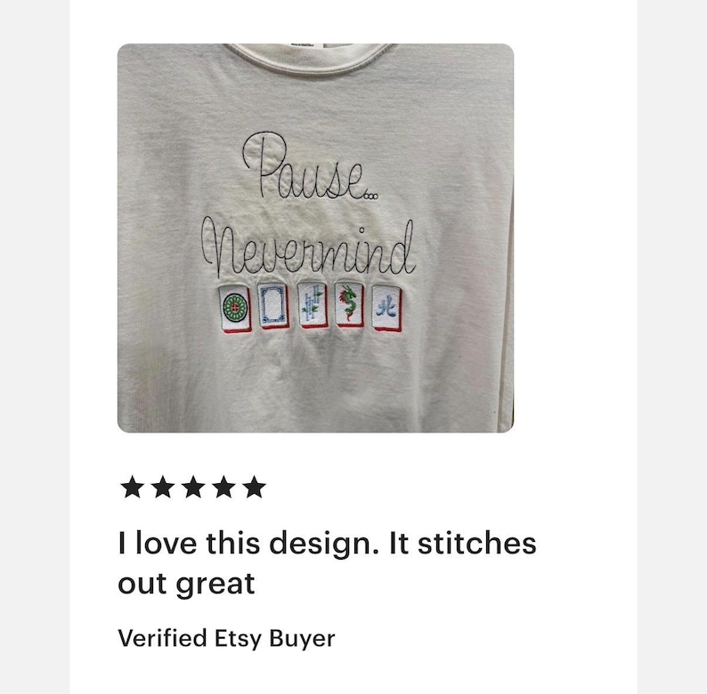 May include: A light gray long-sleeve shirt with the embroidered text "Pause... Nevermind". Below the text are embroidered images of Mahjong tiles. The shirt has a crew neck.