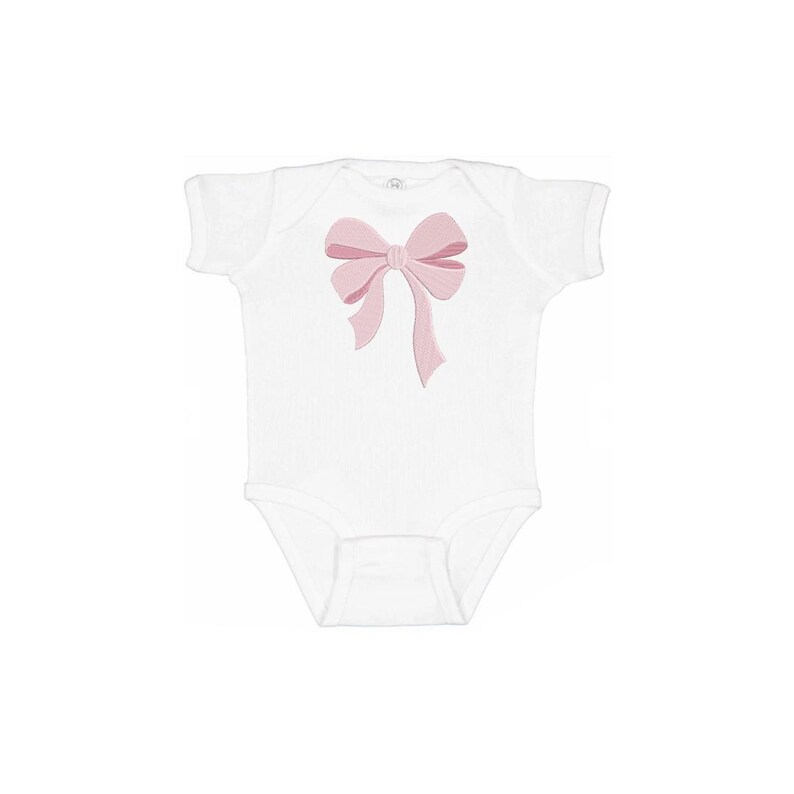 Peut inclure: Un body blanc &agrave; manches courtes orn&eacute; d'un motif de n&oelig;ud rose clair brod&eacute; au centre. Le v&ecirc;tement pr&eacute;sente une encolure ronde et une fermeture &agrave; boutons-pression &agrave; l'entrejambe, offrant un design &eacute;pur&eacute; sur un tissu blanc uni.