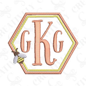 May include: Embroidered monogram with a bee design. The monogram is in a hexagon shape with a double outline. The letters are "KG" in a script font. The bee is on the left side of the hexagon.