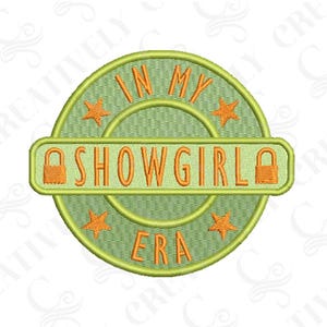 Peut inclure: Écusson brodé avec l'inscription "IN MY SHOWGIRL ERA" en orange sur un fond circulaire vert. Le design comprend des étoiles et des cadenas orange, créant une esthétique vintage et théâtrale.