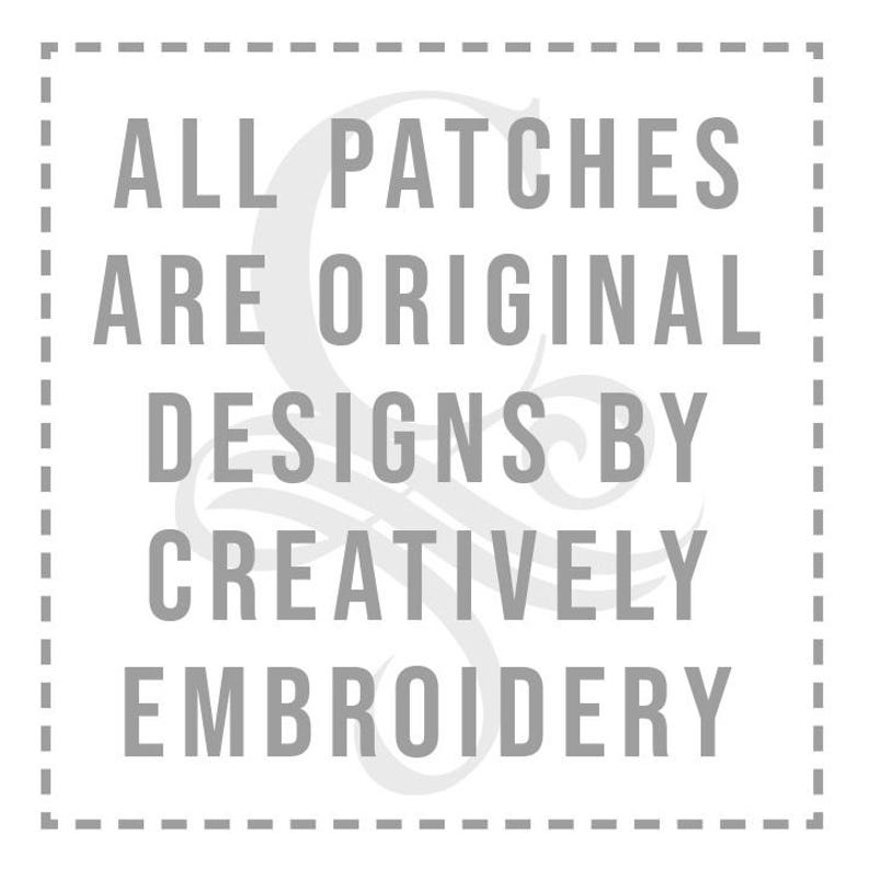 May include: A square image with a dashed border contains the text: "ALL PATCHES ARE ORIGINAL DESIGNS BY CREATIVELY EMBROIDERY" in a gray, sans-serif font. The text is centered within the square.