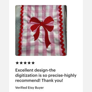 Peut inclure: Une pi&egrave;ce de tissu rectangulaire avec un motif &agrave; carreaux vichy rose et blanc. Le centre pr&eacute;sente un n&oelig;ud brod&eacute; rouge avec des accents rose clair. Les bords verticaux sont finis avec une bordure d&eacute;corative festonn&eacute;e rouge.