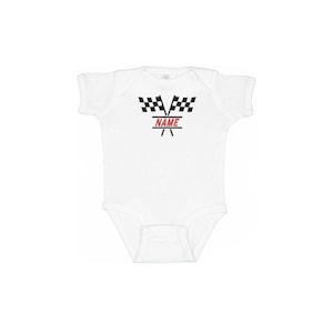 May include: White baby onesie with a racing theme. The design features two black and white checkered flags above the word "NAME" in red, with a red and black racing stripe design below. A cute outfit for a baby.