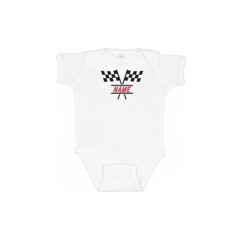 May include: White baby onesie with a racing theme. The design features two black and white checkered flags above the word "NAME" in red, with a red and black racing stripe design below. A cute outfit for a baby.