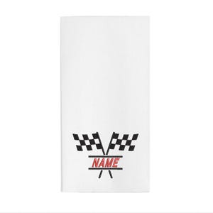 May include: White rectangular towel with a black and white checkered flag design and the word "NAME" in red. The towel has a racing theme.