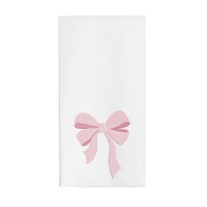 Peut inclure: Une serviette en tissu blanc rectangulaire orn&eacute;e d'un n&oelig;ud rose clair brod&eacute; au centre. Le motif du n&oelig;ud pr&eacute;sente des lignes cousues d&eacute;taill&eacute;es qui cr&eacute;ent une impression de profondeur et de texture, plac&eacute; vers la moiti&eacute; inf&eacute;rieure du tissu blanc.