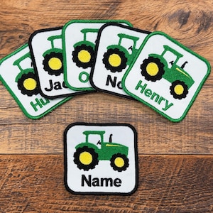 May include: Embroidered patches featuring a green tractor design with yellow wheels on a white background. Several patches have names like "Henry" and "Jack". One patch reads "Name". The patches have a black border.