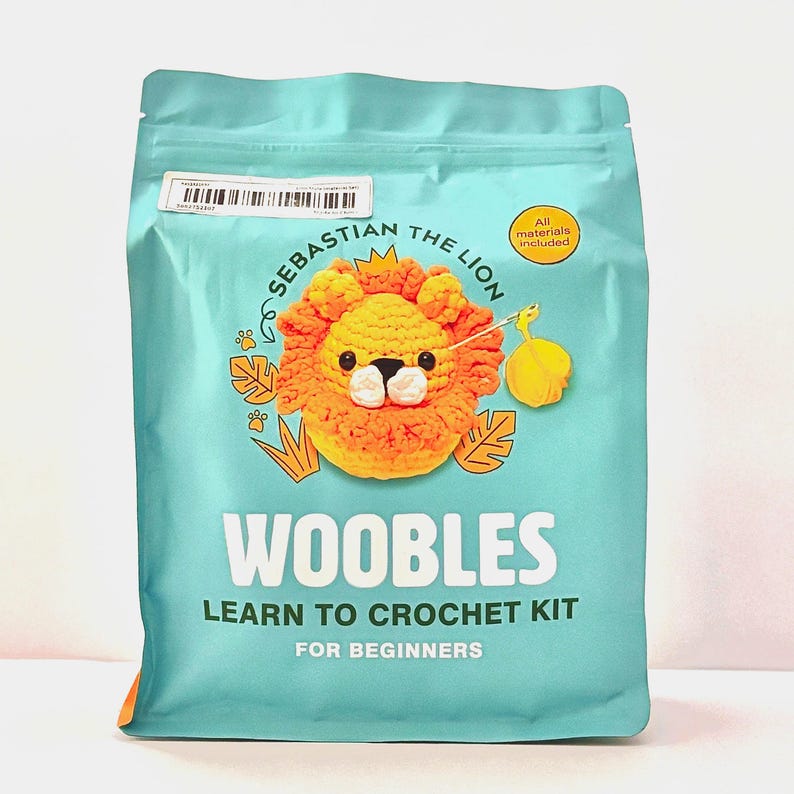 May include: A teal package featuring a crochet lion named Sebastian. The package reads "Woobles Learn to Crochet Kit for Beginners." A yellow circle indicates "All materials included."
