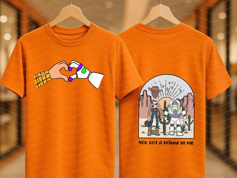 Pu&ograve; includere: T-shirt arancione con un cuore formato da una mano umana e una mano robotica. Il retro della maglietta presenta una scena desertica con due personaggi dei cartoni animati e la scritta "YOU GOT A FRIEND IN ME".