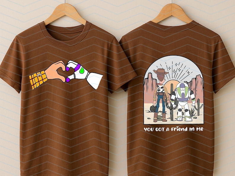 Pu&ograve; includere: T-shirt marrone con un cuore fatto di mani dei cartoni animati, una con un motivo giallo e marrone e l'altra bianca con accenti viola e verdi. Il retro della maglietta mostra Woody e Buzz Lightyear con la scritta "you got a friend in me".