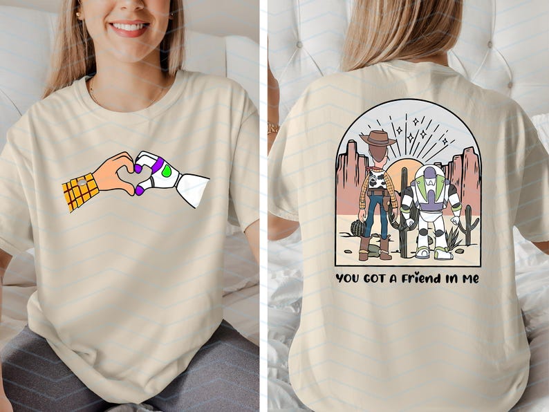 Pu&ograve; includere: T-shirt beige con un cuore formato da mani di cartoni animati, una con una manica a quadri e l'altra robotica. Il retro della maglietta mostra una scena desertica con due personaggi e la scritta "YOU GOT A FRIEND IN ME".