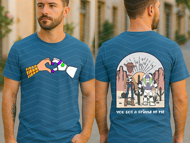 Pu&ograve; includere: T-shirt blu teal con una grafica di due mani che formano un cuore, una umana e una robotica. Il retro della maglietta mostra Woody e Buzz Lightyear in una scena desertica con la scritta "you got a friend in me."