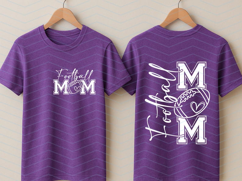 May include: Purple t-shirt with a white graphic that says "Football Mom" with a football and heart design. The back of the shirt has the words "A Football Mom" with a football and heart design.