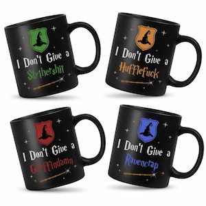 May include: Four black ceramic mugs with white text and colorful crests. Each mug has a different phrase: "I Don't Give a Slythershit", "I Don't Give a Hufflefuck", "I Don't Give a Griffindamn", and "I Don't Give a Ravencrap".