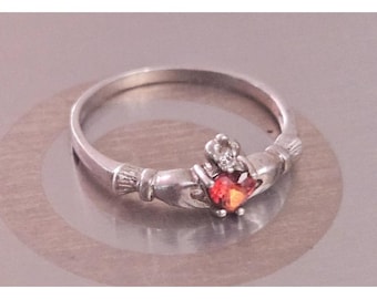 Anillo Claddagh de plata de ley con banda en forma de corazón de granate y detalle de circonita cúbica.