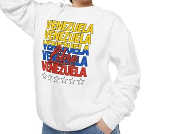 May include: White sweatshirt with the word "VENEZUELA" in yellow, blue, and red, with the word "Libre" in red script. Below the text are six white outlined stars. The sweatshirt is a long-sleeved crew neck.