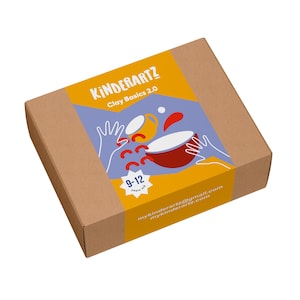 May include: A brown cardboard box with a yellow and blue label. The label reads "KINDERARTZ Clay Basics 2.0" with illustrations of clay objects. The box is designed for children aged 9-12 and includes the email address mykinderartz@gmail.com.