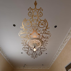 Puede incluir: Diseño de techo dorado ornamentado con una lámpara de araña central y molduras decorativas. El techo está pintado de blanco con detalles dorados, creando una estética lujosa y elegante. El diseño incluye patrones florales y de volutas.