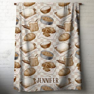 May include: A beige and white checkered curtain featuring a watercolor pattern of baking tools and bread. The design includes images of dough, bowls, loafs, rolling pins, and the name "JENNIFER".