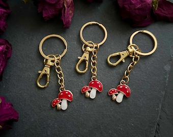 May include: Three gold keyrings with red and white mushroom charms. Each keyring has a gold ring and a gold lobster clasp.