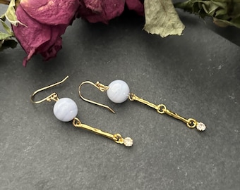 May include: A pair of gold dangle earrings with light blue agate beads and small clear rhinestones.