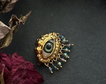 Broche con forma de ojo llamativo - Latón tono dorado, dijes de cristal azul oscuro - Joyería surrealista y espeluznante, broche decorativo ecléctico, peculiar e inusual