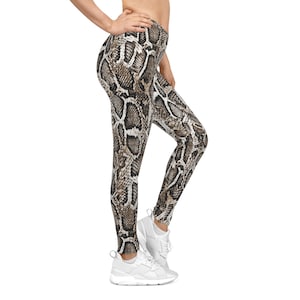 Op de afbeelding: Hoge taille leggings met een slangenprint in bruin, zwart en wit. De leggings zijn nauwsluitend en gemaakt van een rekbaar materiaal. Het model draagt witte sneakers.
