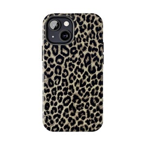 Pode incluir: Uma capa de telefone com estampa de leopardo. A capa apresenta um padrão de manchas pretas e bege sobre um fundo bege. A capa do telefone tem um recorte para a câmera e o flash na parte traseira.