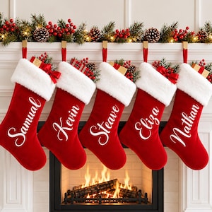 May include: Five red velvet Christmas stockings with white faux fur cuffs, each personalized with white cursive names: Samual, Kevin, Steave, Eliza, and Nathan. Each stocking is topped with a small gift box and red berry accents.