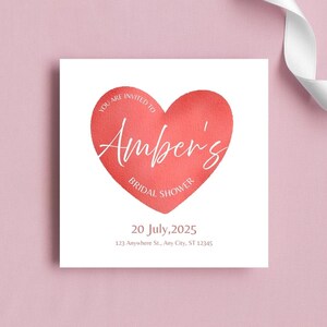 May include: A square invitation card featuring a coral heart design. The text "YOU ARE INVITED TO Amber's BRIDAL SHOWER" is displayed on the heart. The date "20 July, 2025" and address are also included.