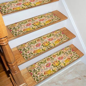 May include: Stair treads with a floral design, featuring yellow tulips and pink flowers on a cream background. The rectangular treads are placed on wooden stairs with a wooden handrail.