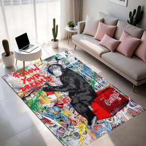 May include: A colorful area rug featuring a chimpanzee holding a can of Campbell's soup and sitting on a red Coca-Cola cooler. The rug has the text "Follow Your Dreams" and a vibrant, abstract design.