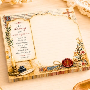 May include: A square notepad featuring a vintage parchment design with lined paper. The left side displays the text Be strong and courageous. Do not be afraid or discouraged, for the Lord your God is with you wherever you go. JOSHUA 1:9, a candle, and a quill.