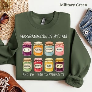 May include: Military green sweatshirt with the text "PROGRAMMING IS MY JAM" and colorful jars labeled with programming languages like C++, Python, and Javascript. The phrase "AND I'M HERE TO SPREAD IT" is also included.