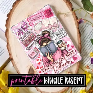 May include: A pink Kindle insert with a design featuring a woman reading a book, coffee cup, and the text "PLEASE DO NOT DISTURB." The insert is decorated with hearts, bows, and the words "Fueled By Romance Books."