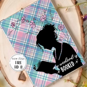 Peut inclure: Une coque transparente pour tablette Fire HD 8 avec un motif à carreaux bleu pastel, rose et blanc. Une silhouette noire d'une personne lisant un livre est présente, avec le texte "my weekend is BOOKED".