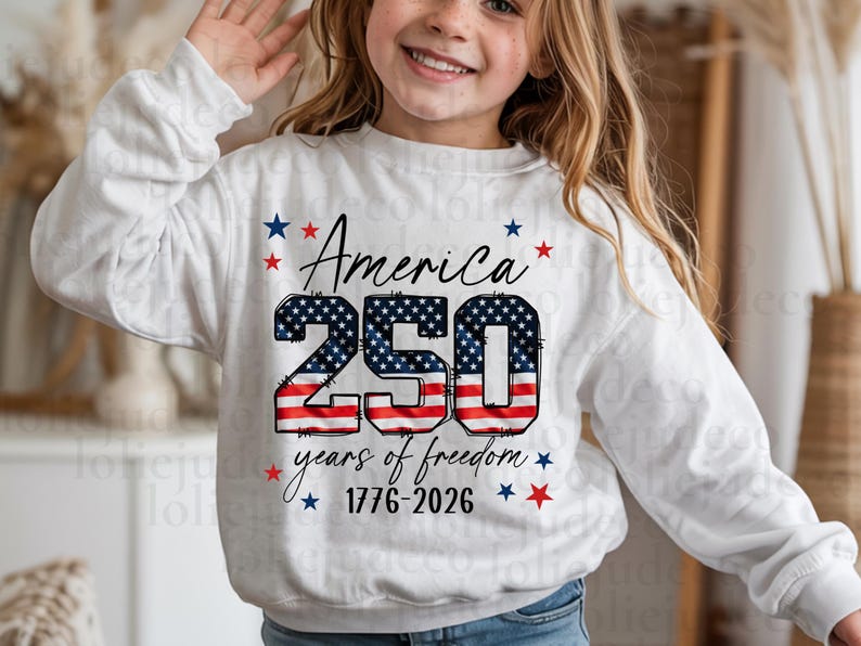 May include: A white long-sleeve sweatshirt featuring a graphic with the text America 250 years of freedom 1776-2026. The number 250 is filled with a red, white, and blue American flag pattern, surrounded by small red and blue stars.