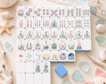 May include: A set of white mahjong tiles featuring colorful ocean-themed illustrations, including seashells, coral, sea creatures, and nautical symbols. The tiles are arranged in a grid, with some blank tiles and one blue tile placed separately.