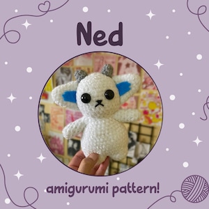 May include: A white amigurumi doll with black eyes, gray horns, and blue accents on the ears. The doll is held in a hand and is centered in a circular frame. The word "Ned" is above the doll, and "amigurumi pattern!" is below.