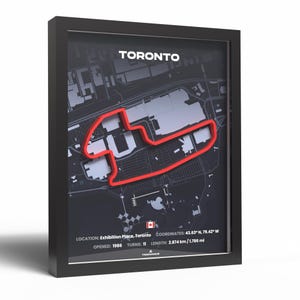 May include: Black framed print of the Toronto race track map, with a red outline against a dark grey backdrop. Text at the top reads "TORONTO". Additional details include location, coordinates, opening year, turns, and a length of 2.874 km.