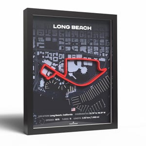 May include: Framed map art of the Long Beach Grand Prix circuit in California. The track is highlighted in red against a gray and black background, with the city layout visible. The frame is black, and the text "LONG BEACH" is at the top.